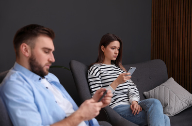 Photo of Couple addicted to smartphones ignoring each other at home. Relationship problems