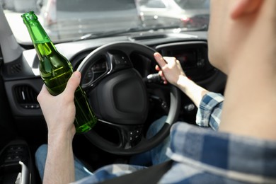 Man with bottle of beer driving car, closeup. Don't drink and drive concept