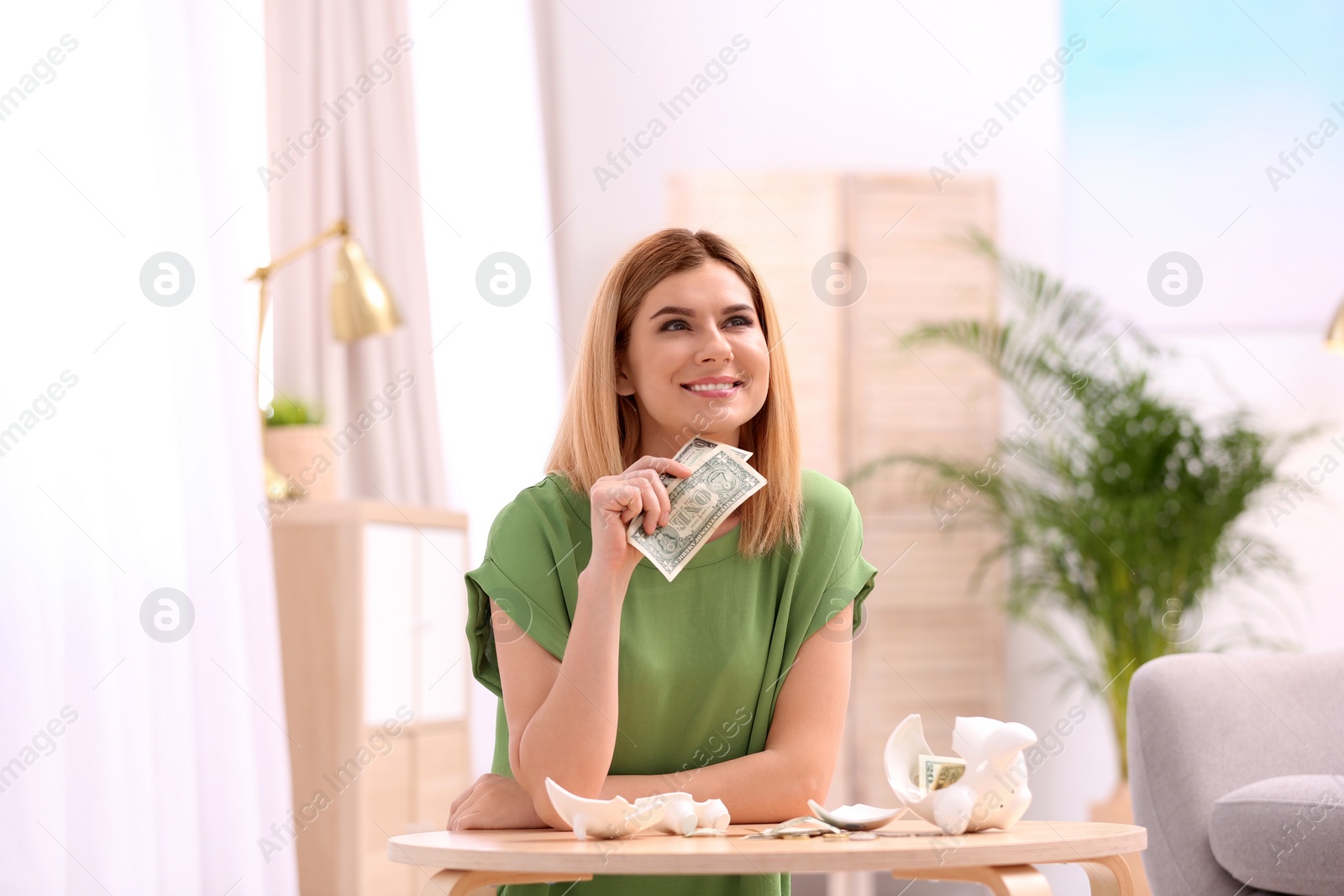 Photo of Woman with broken piggy bank and money at home