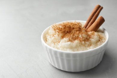 Delicious rice pudding with cinnamon on light table, closeup. Space for text