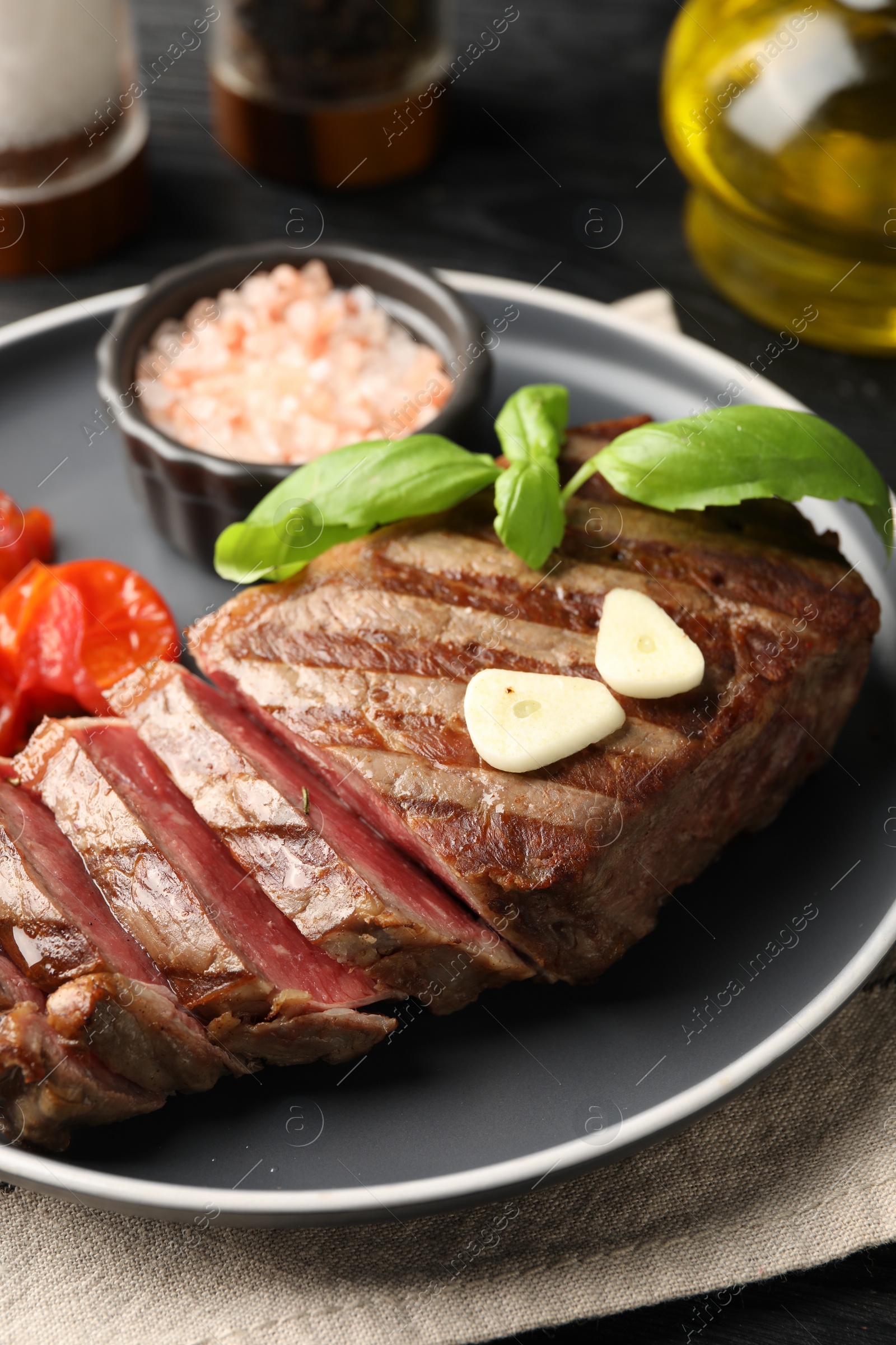 Photo of Delicious grilled beef steak served with spices on table, closeup