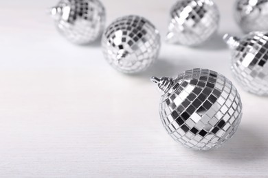 Photo of Shiny disco balls on white wooden background. Space for text