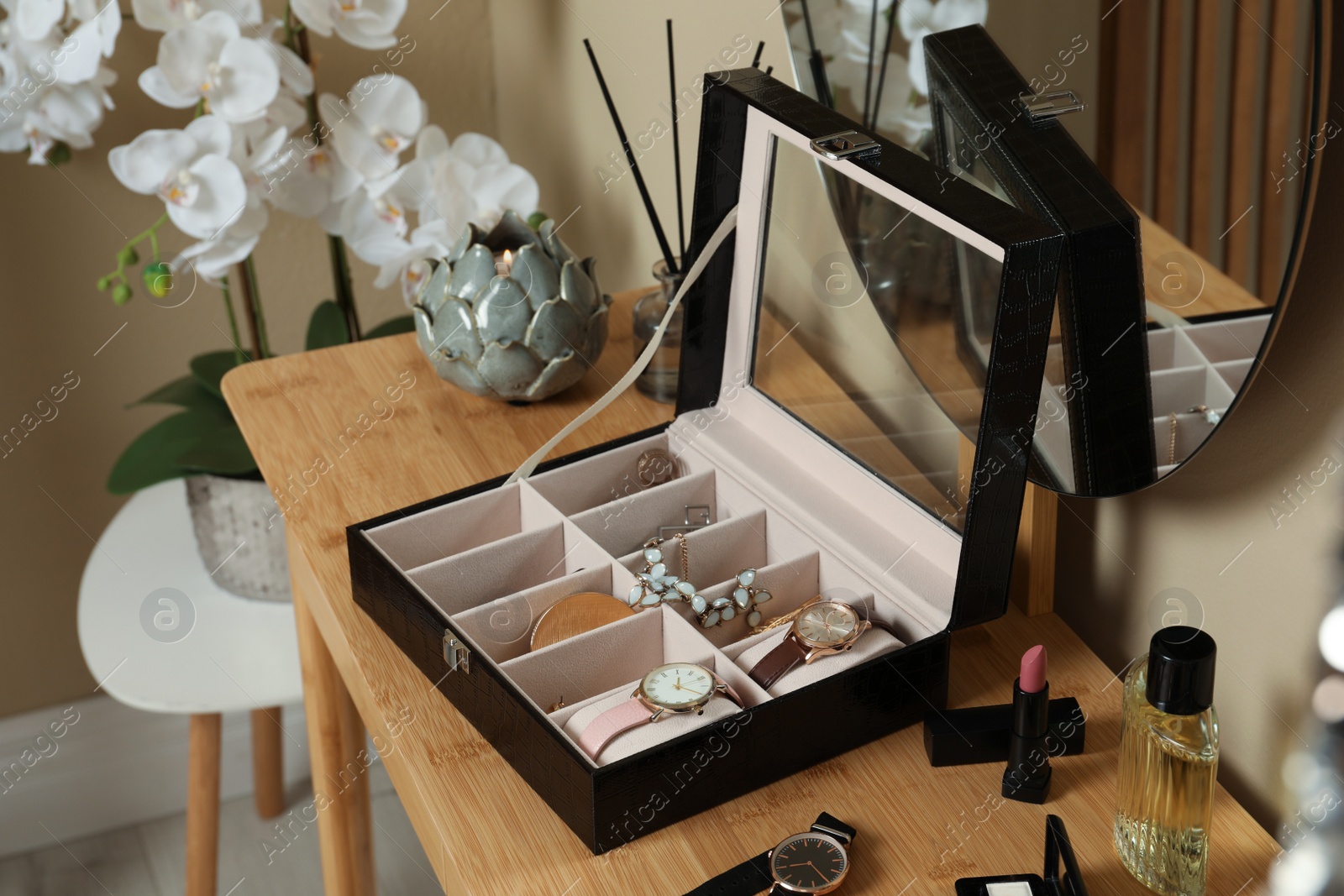 Photo of Elegant jewelry box with beautiful bijouterie, cosmetics and stylish accessories on dressing table in room