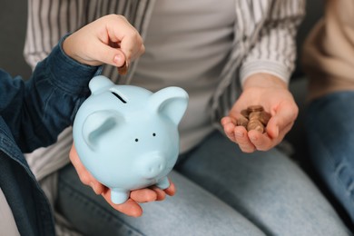 Photo of Family budget. Little boy and his parents putting coins into piggy bank, closeup