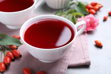 Photo of Fresh rose hip tea and berries on light table, closeup