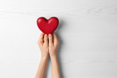 Photo of Woman holding decorative heart on white background, top view. Space for text