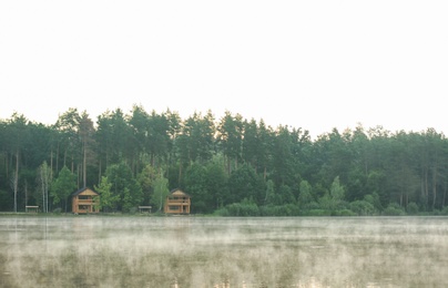 Beautiful landscape with forest and houses near lake. Camping season