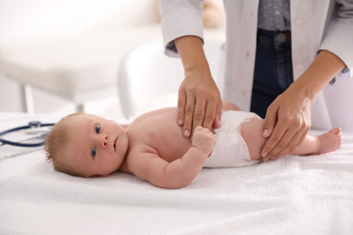 Photo of Doctor examining cute baby indoors, closeup. Health care