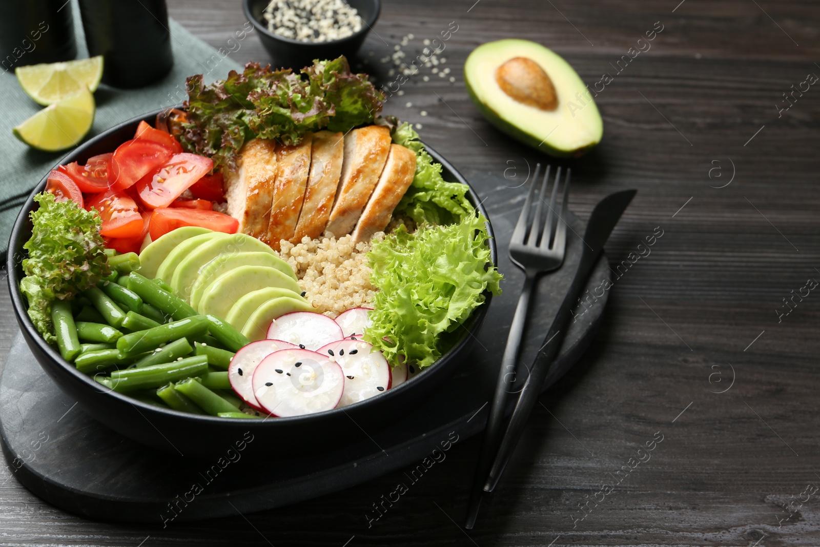 Photo of Healthy meal. Tasty products in bowl and cutlery on black wooden table, space for text