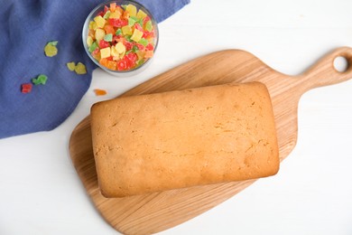 Delicious cake with candied fruits on white wooden table, flat lay