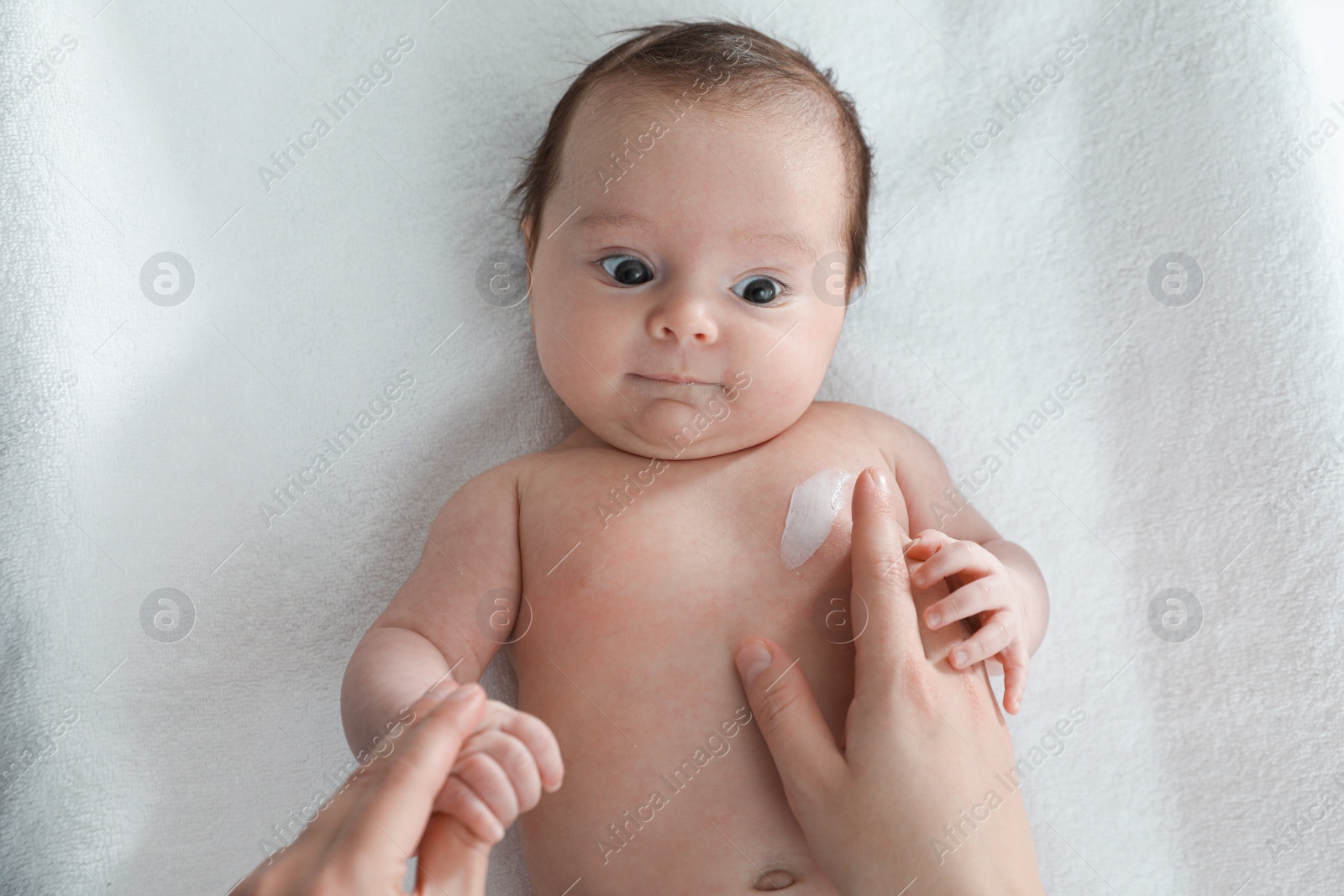 Photo of Mother applying body cream on her little baby, top view