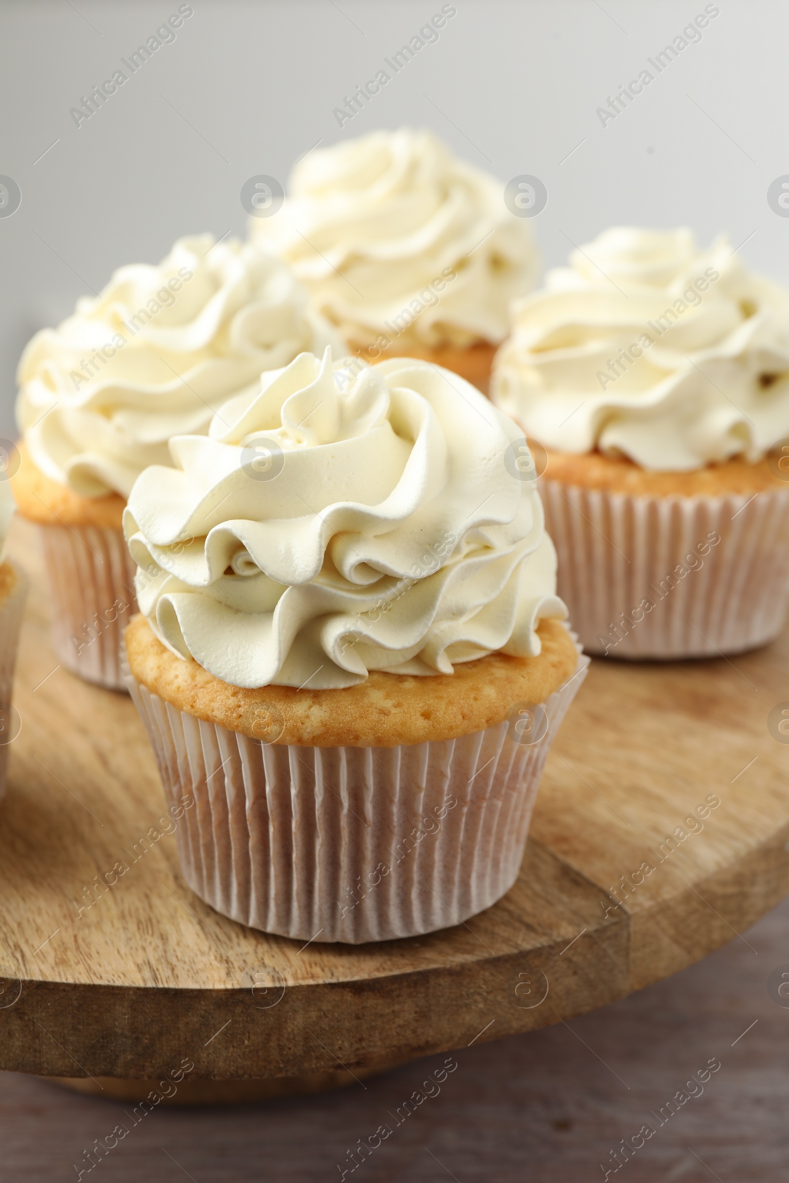 Photo of Tasty cupcakes with vanilla cream on pink wooden table, closeup