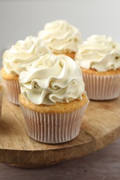 Photo of Tasty cupcakes with vanilla cream on pink wooden table, closeup