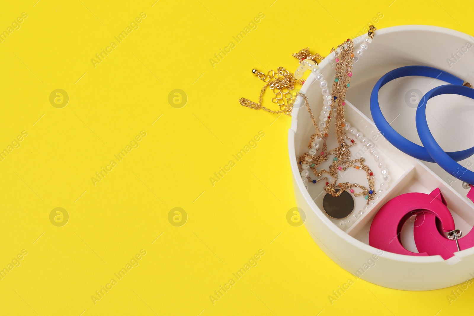 Photo of Jewelry box with many different accessories on yellow background, space for text