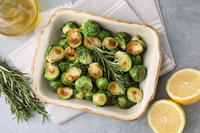 Photo of Delicious roasted Brussels sprouts, rosemary and lemon on grey table, top view