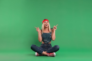 Photo of Portrait of happy hippie woman pointing at something on green background