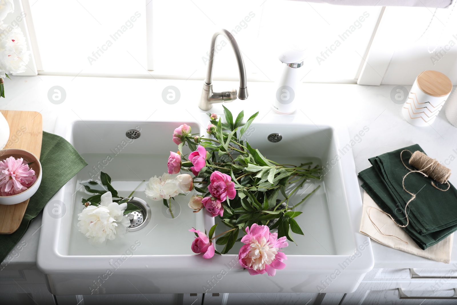 Photo of Bunch of beautiful peonies in kitchen sink, above view