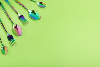 Flat lay composition with cutlery on light green background, space for text