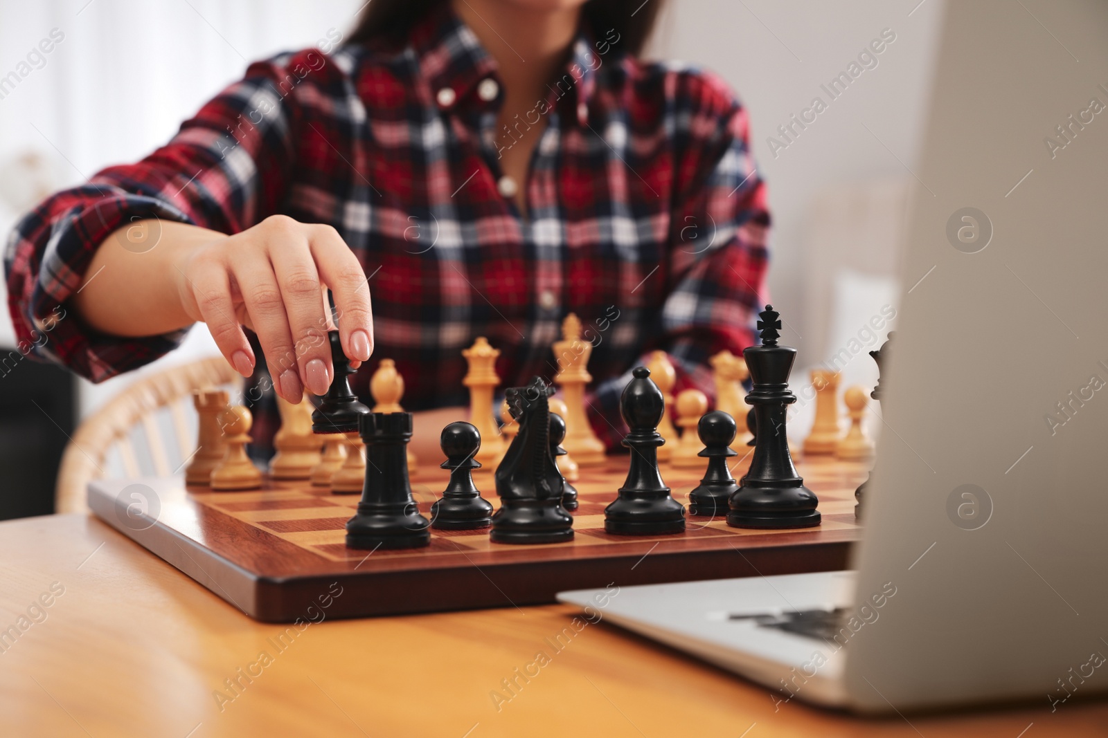 Photo of Woman playing chess with partner through online video chat at table indoors, closeup