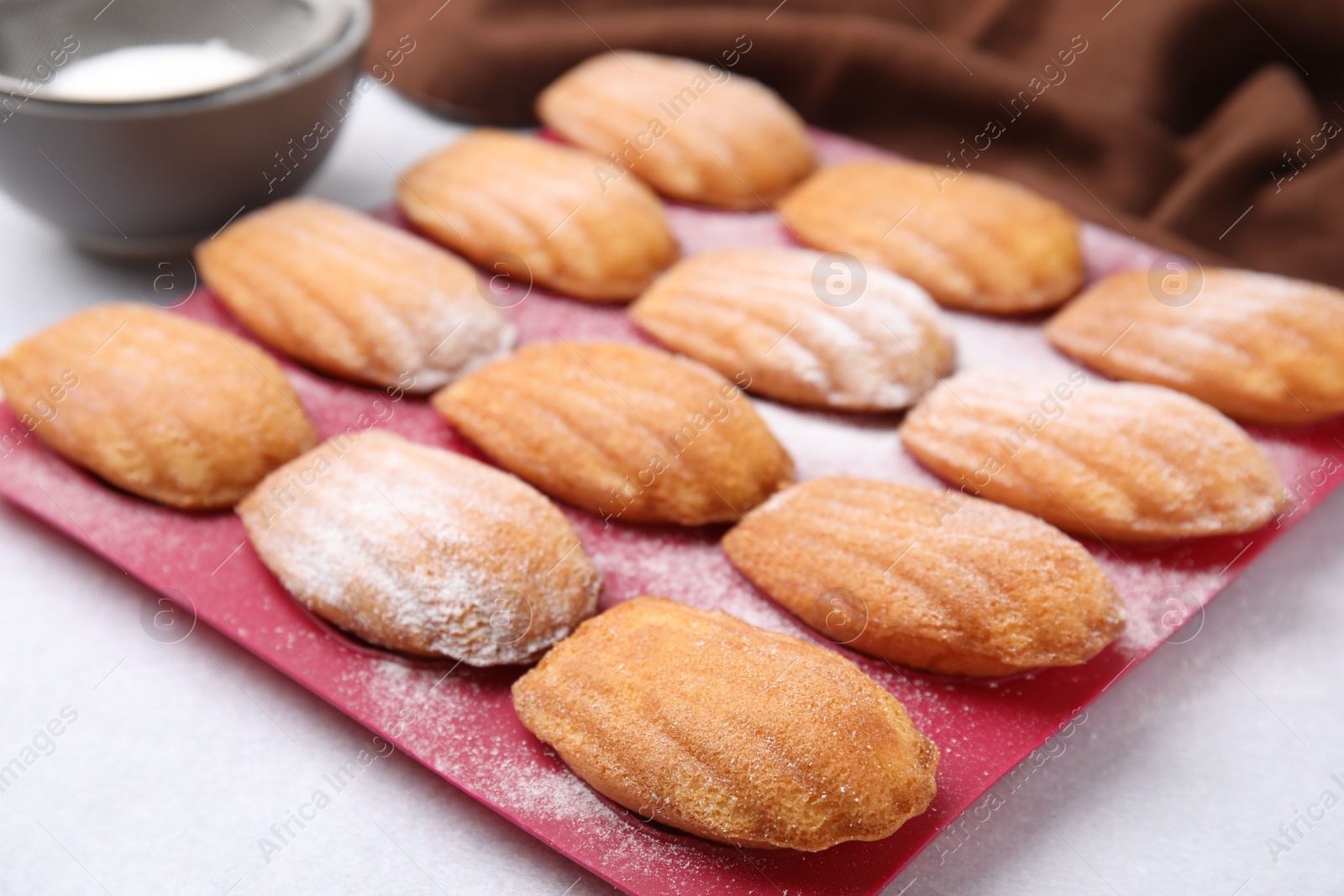 Photo of Delicious madeleine cookies in baking mold on white table, closeup