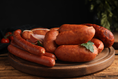 Photo of Different tasty sausages on wooden table, closeup