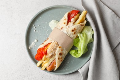 Delicious pita wrap with sausage, french fries and vegetables on light gray table, top view