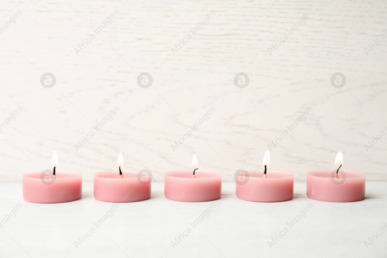 Photo of Pink wax candles on white table, space for text