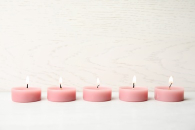 Pink wax candles on white table, space for text