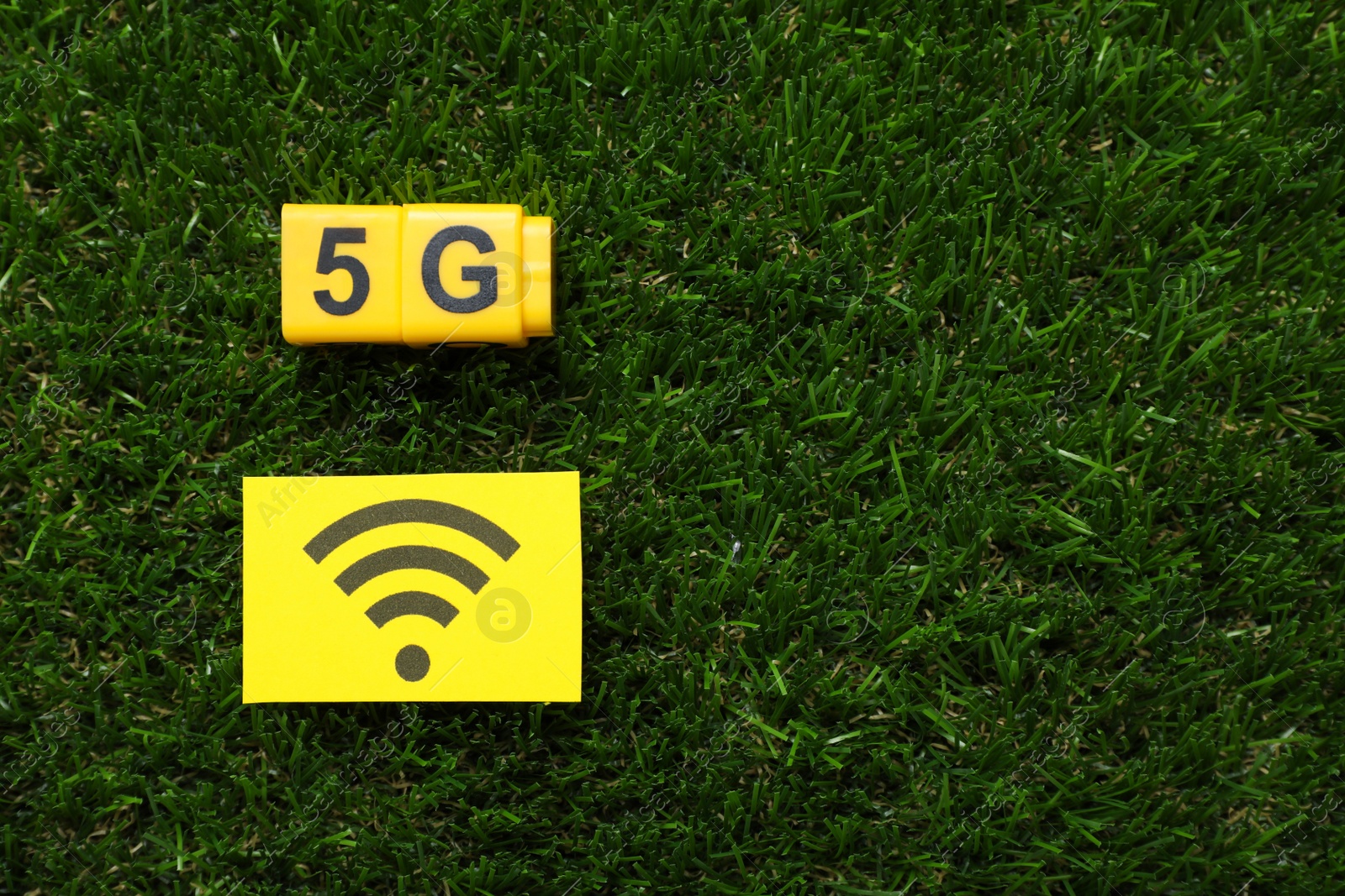 Photo of 5G technology, Internet concept. Yellow cubes and card with WiFi symbol on green grass, flat lay. Space for text