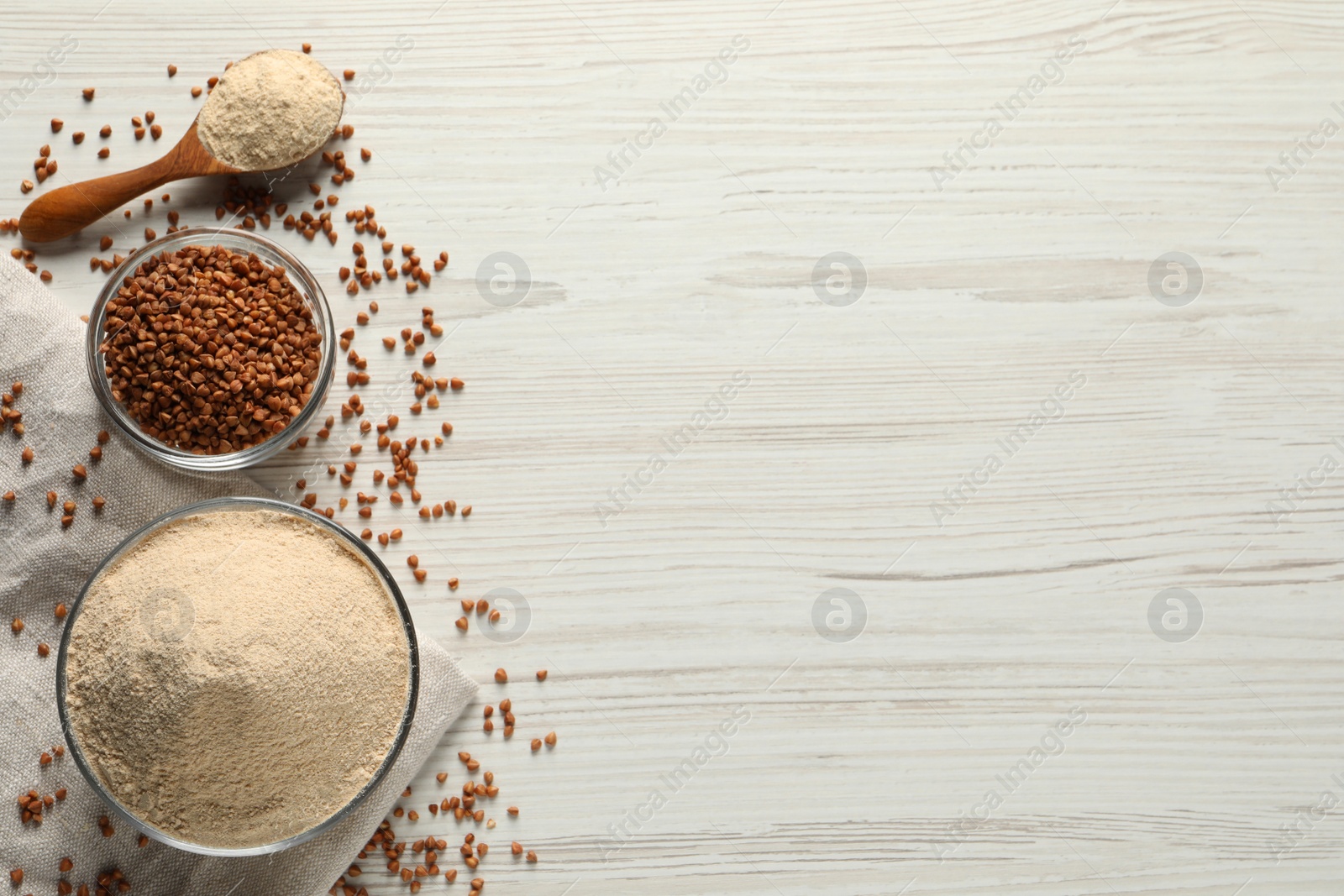 Photo of Buckwheat flour on white wooden table, flat lay. Space for text