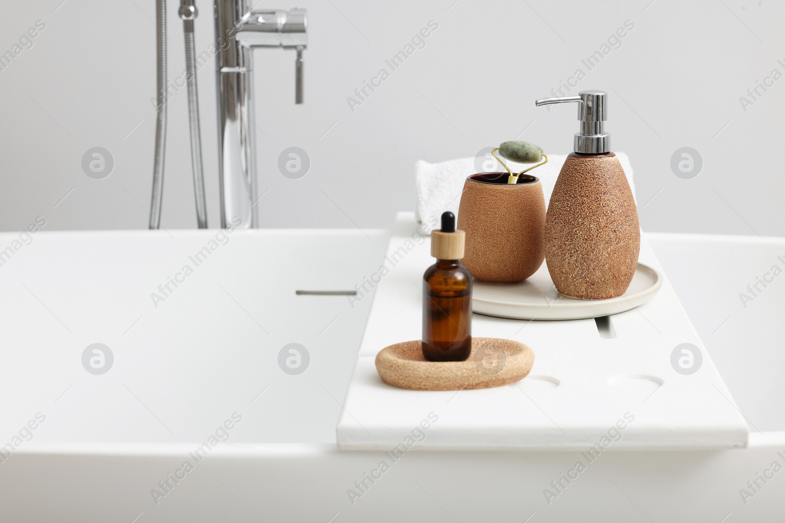 Photo of Different personal care products and accessories on bath tub in bathroom, space for text