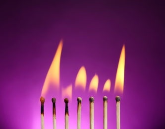 Line of burning matches on color background