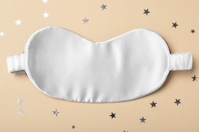 Photo of White sleeping mask and glitter on yellow background, flat lay. Bedtime accessory