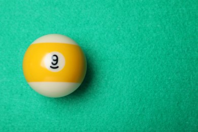 Photo of Billiard ball with number 9 on green table, top view. Space for text