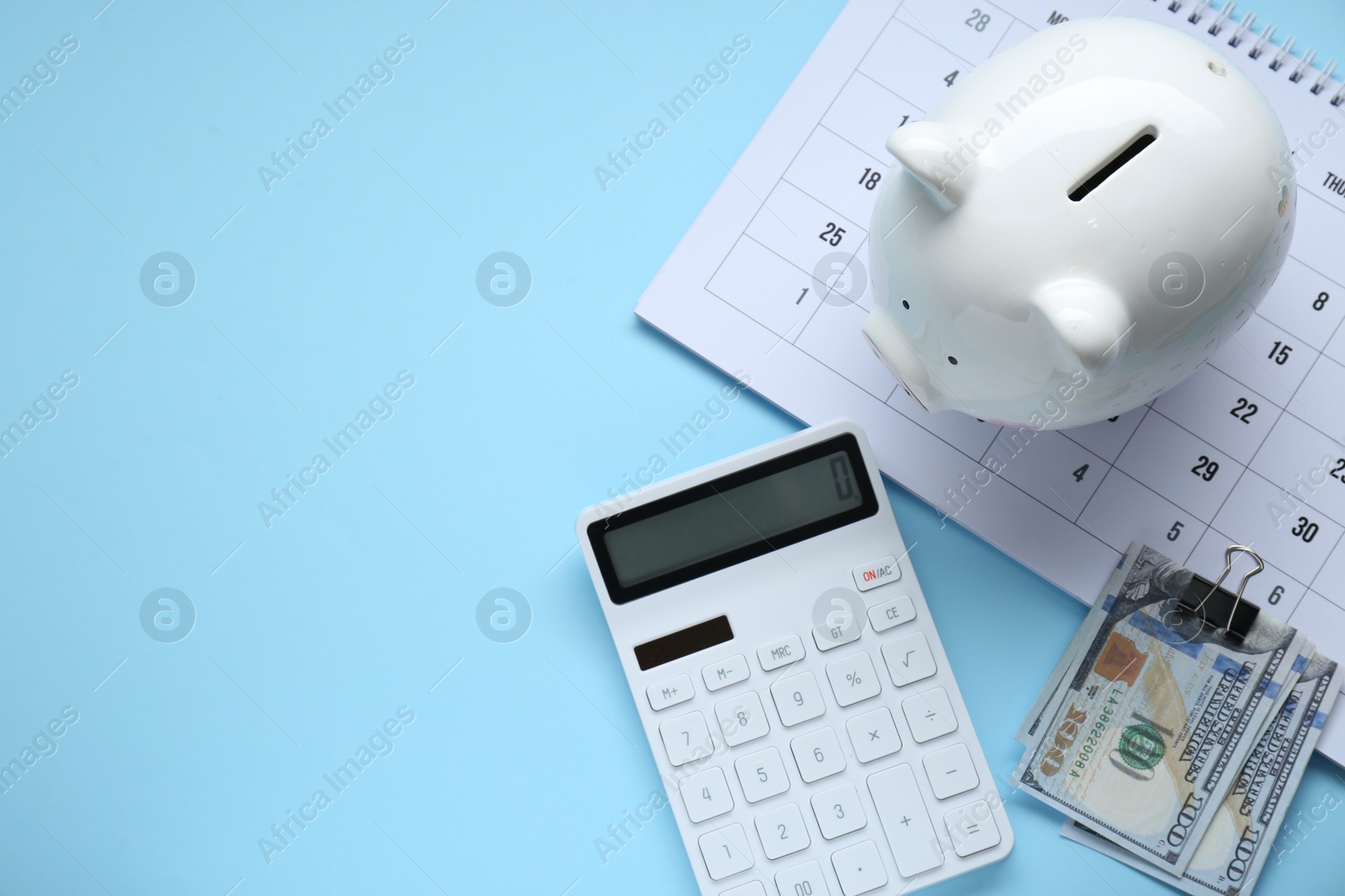 Photo of Flat lay composition with piggy bank and calculator on light blue background. Space for text