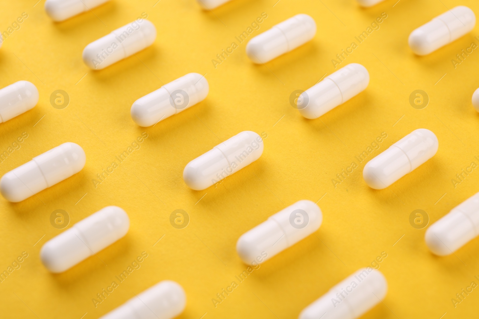 Photo of Many vitamin capsules on orange background, closeup