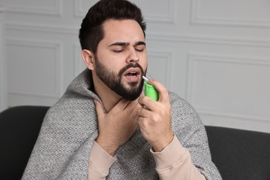 Young man using throat spray at home