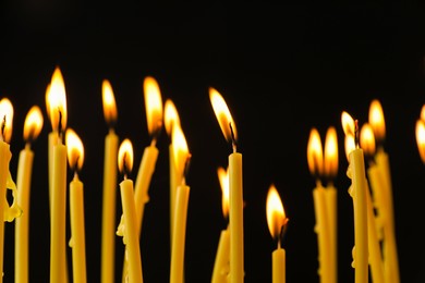 Photo of Many burning church candles on black background