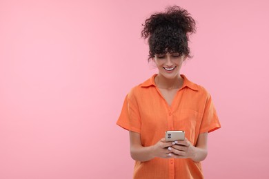 Photo of Woman sending message via smartphone on pale pink background, space for text