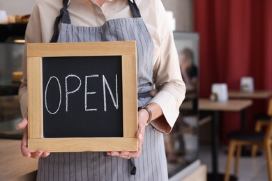 Photo of Business owner holding open sign in her cafe, closeup. Space for text