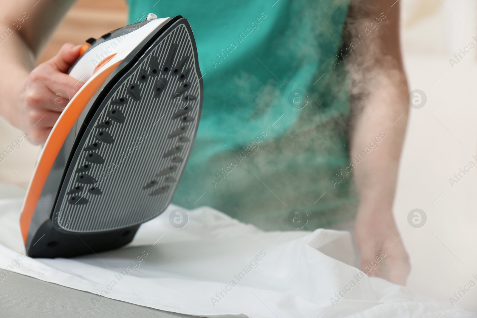 Photo of Woman ironing clean shirt at home, closeup
