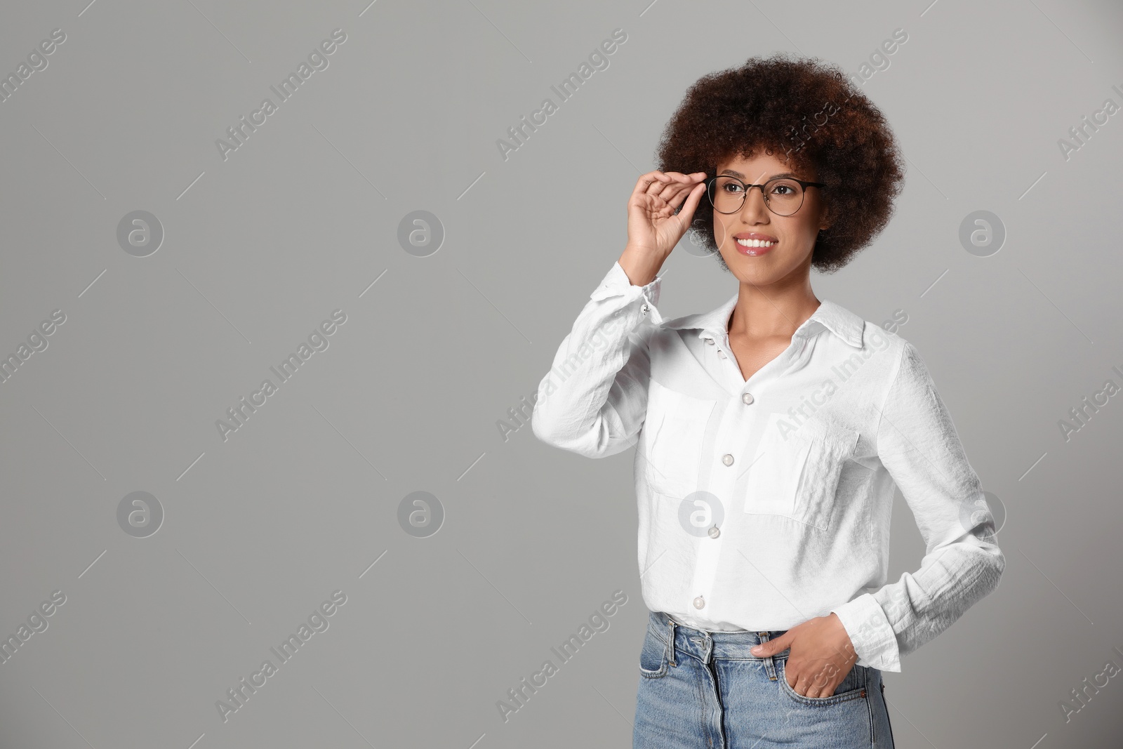 Photo of Beautiful young woman in eyeglasses on grey background. Space for text