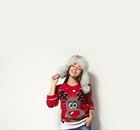 Photo of Young woman in Christmas sweater and hat on white background