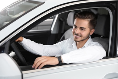 Young man testing new car in salon