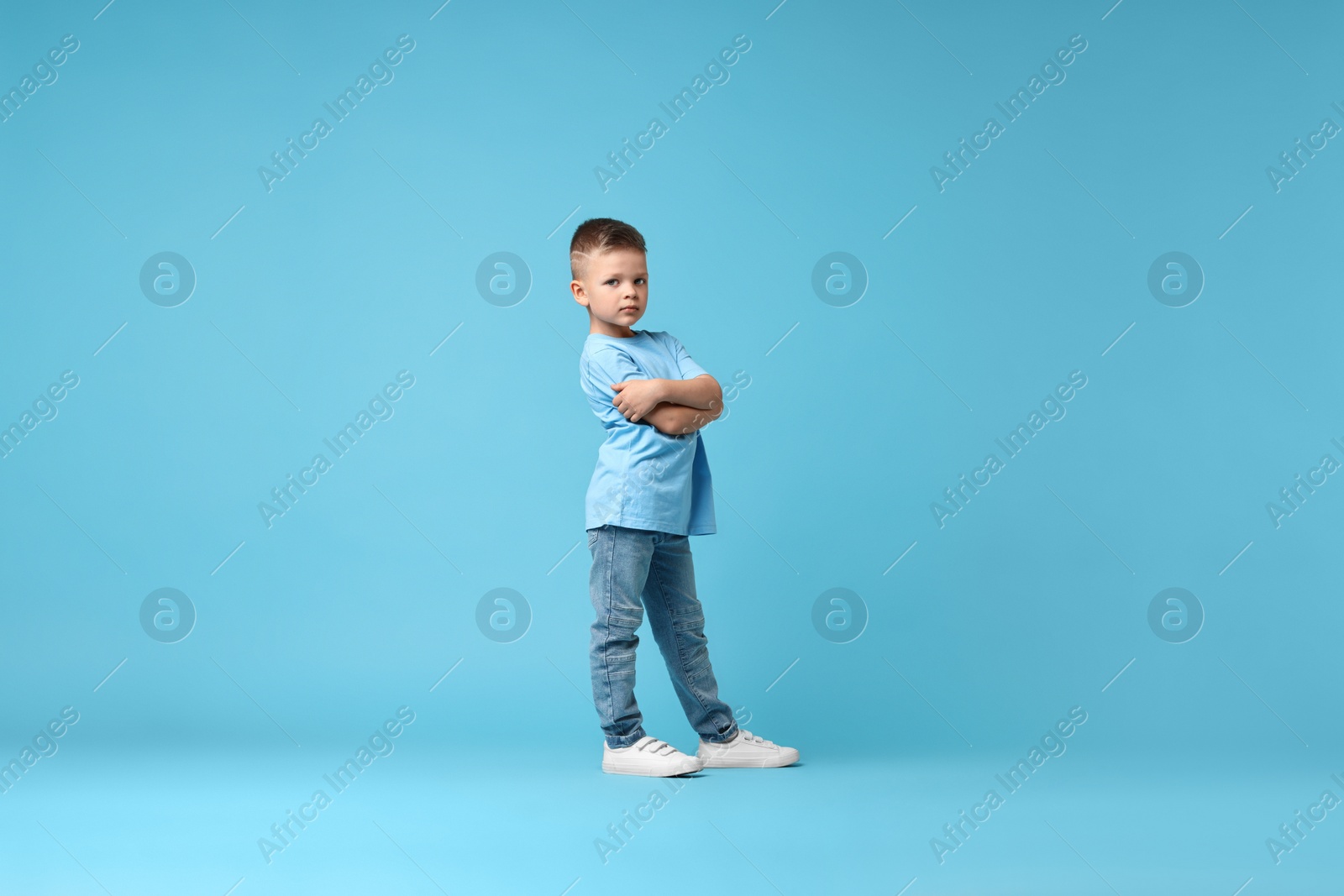 Photo of Happy little boy dancing on light blue background