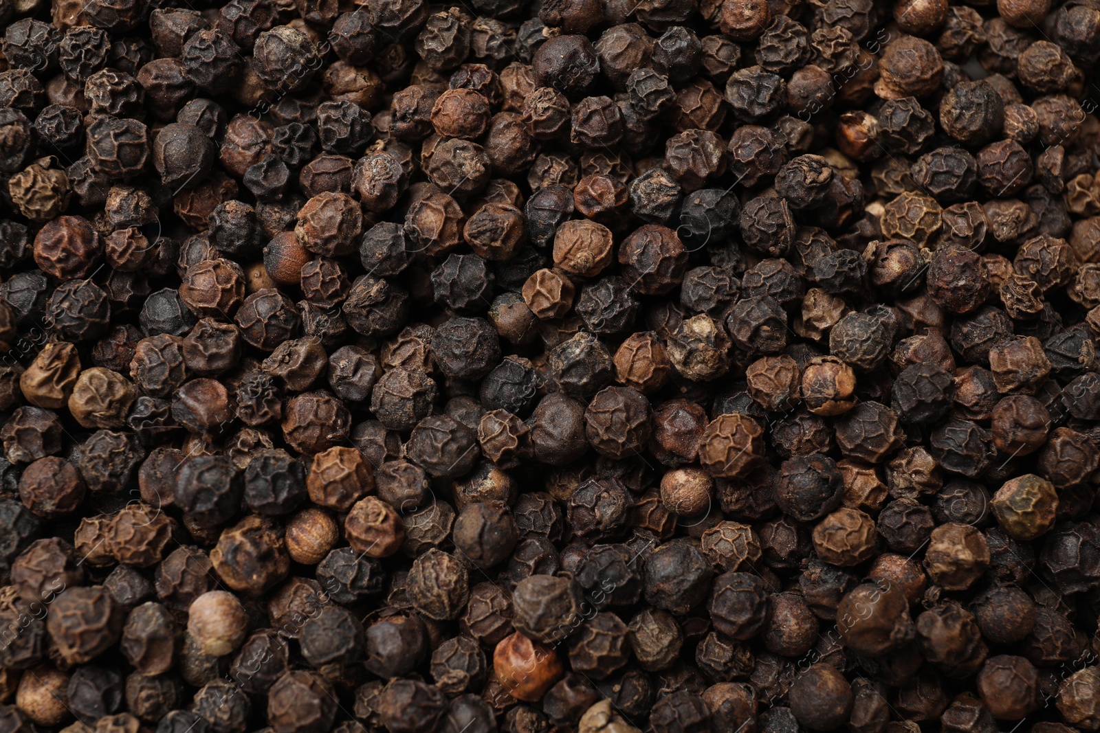 Photo of Aromatic spice. Black peppercorns as background, top view