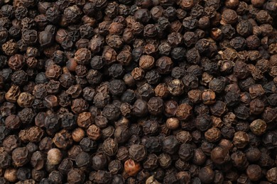 Photo of Aromatic spice. Black peppercorns as background, top view