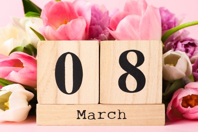 Photo of Wooden block calendar with date 8th of March and tulips on pink background, closeup. International Women's Day