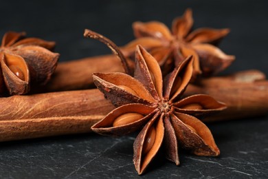 Photo of Aromatic anise stars and cinnamon sticks on black table, closeup