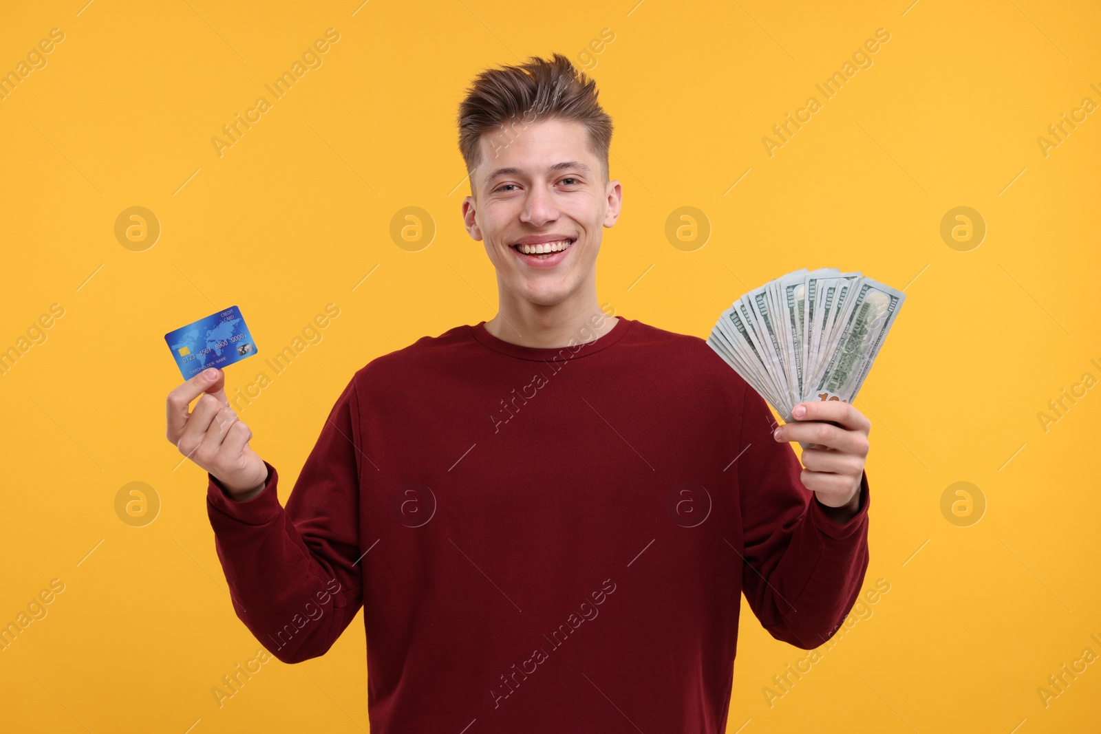 Photo of Happy man with dollar banknotes and credit card on yellow background